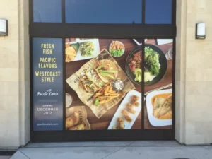 A window signage of different kinds of food dishes from the top view. It has blue windows on the top and restaurant details on the left of the window signage.
