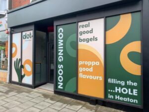 A window signage about 'Coming Soon' for Dot Bagels.
