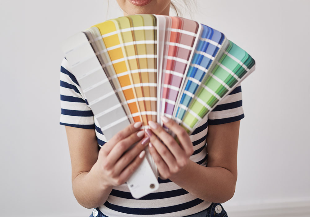 a woman holding a fan of color swatches